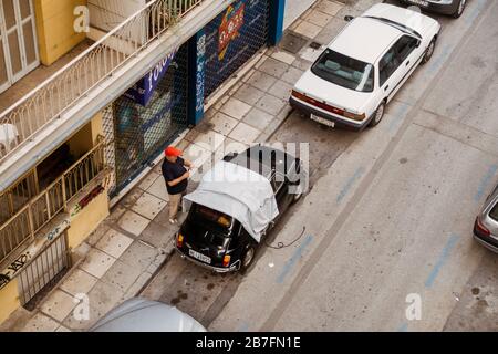 Un homme retire une couverture protectrice de sa Fiat 500 Bambino classique à Thessalonique, Grèce Banque D'Images