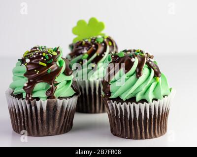 Saint-Patrick's Day chocolat menthe givrée cupcakes avec bruine au chocolat et saupoudrer et un trèfle à quatre feuilles sur le dessus avec un fond blanc. Delicio
