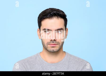 Gros plan portrait de bel homme pensant avec les yeux regardant latéralement isolé sur fond bleu de studio Banque D'Images