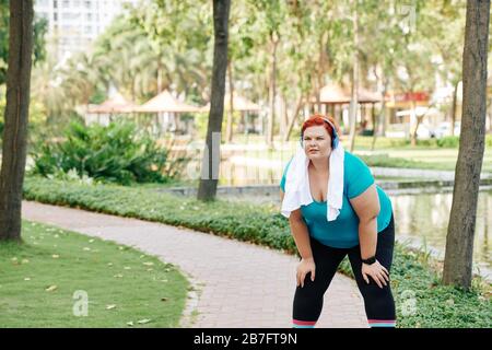 Une jeune femme fatiguée en surpoids qui a fait un court séjour après avoir fait du jogging dans le parc de la ville le matin Banque D'Images