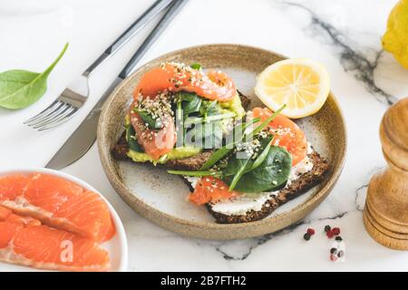 Toasts à l'avocat et au saumon garnis d'épinards et de graines de chanvre. En-cas, hors-d'œuvre ou repas du petit déjeuner sains Banque D'Images