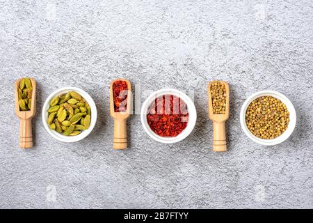 Mélange d'épices aromatiques coriandre, bergamote, paprika en tasses blanches sur un fond gris en béton vue dessus plat laïque nourriture saine. Banque D'Images