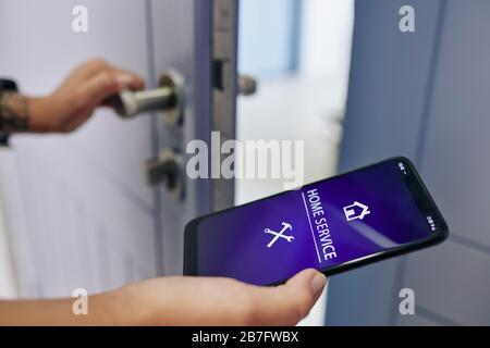 Femme utilisant l'application de service à domicile pour appeler le réparateur pour réparer le verrou de porte Banque D'Images