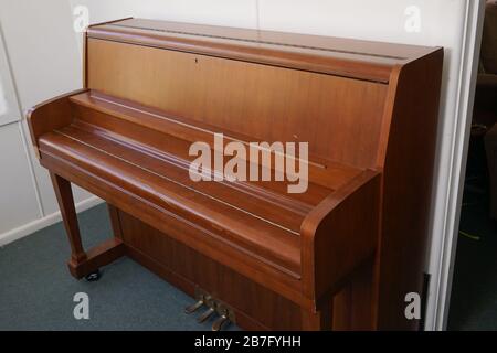 Marron piano contre un mur blanc sous les lumières dans une maison Banque D'Images