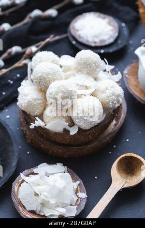 Plan vertical de raffaello brut dans un bol en bois avec morceaux de noix de coco et une cuillère en bois Banque D'Images