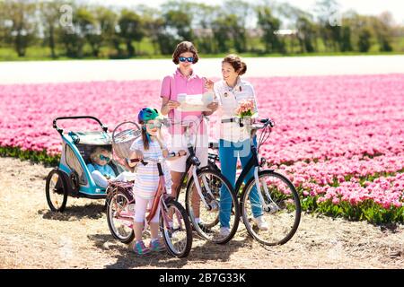 Heureux famille néerlandaise riding bicycle in tulip champs de fleurs en Hollande. Mère et enfants sur des vélos à la floraison des tulipes en Hollande. Bébé en vélo. Banque D'Images