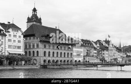 Lucerne, Suisse - 7 mai 2017 : paysage côtier avec tour d'horloge de l'hôtel de ville sur fond. Les gens ordinaires marchent dans la rue. Noir et blanc Banque D'Images