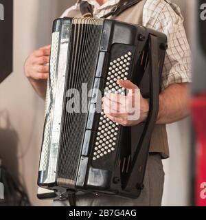 Fond musical en direct. L'accordéoniste joue de l'accordéon noir vintage. Gros plan photo carrée Banque D'Images