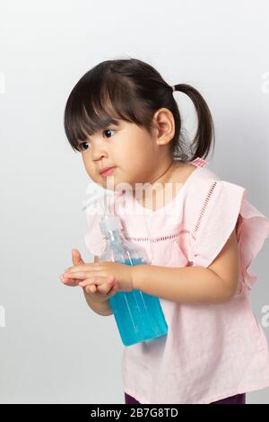Fille asiatique utilisant du gel antiseptique d'alcool pour nettoyer les mains pour prévenir l'infection de l'éclosion de Covid-19. Banque D'Images