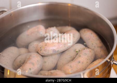 Fabrication de saucisses blanches bavaroises à la maison, chaîne de saucisses bouillantes dans le pot avec de l'eau chaude Banque D'Images