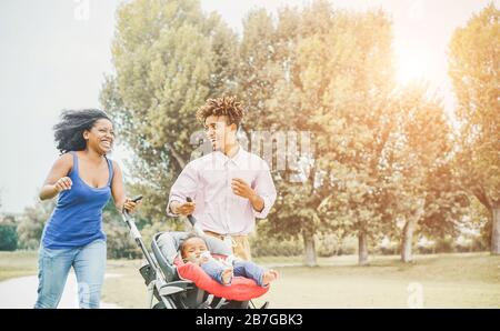 Une famille noire heureuse qui s'amuse à courir dans le parc public extérieur - les parents et leur fille qui aiment le temps ensemble - l'amour, le moment tendre et le bonheur c Banque D'Images