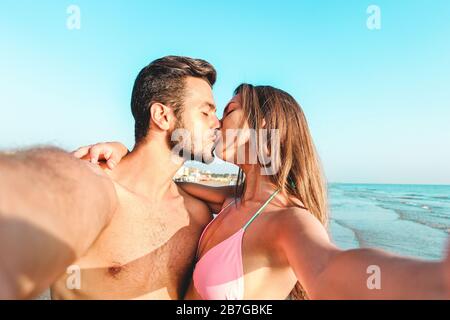 Un couple de voyage heureux qui fait du selfie avec la plage en arrière-plan - concept millénaires petite amie et petit ami en vacances d'été - jeunes gens ayant Banque D'Images