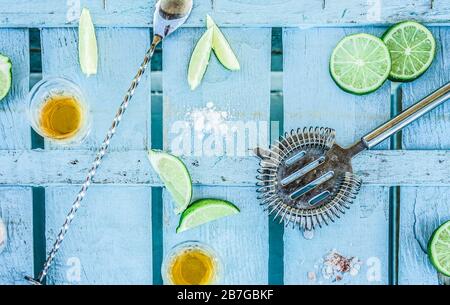 Vue de dessus des prises de vue de tequila avec des limes et du sel sur le comptoir de bar en bois bleu - latin, été, cocktails, boissons, fête et concept de personnes - foyer principal sur s Banque D'Images