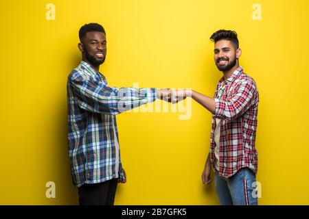 Portrait de deux jeunes hommes heureux donnant une bosse de poing isolée sur fond jaune Banque D'Images