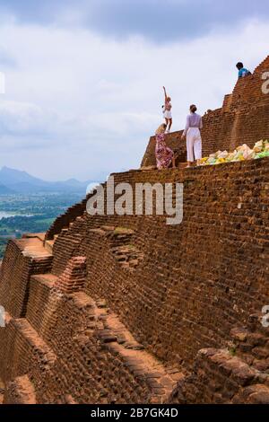 Asie Sri Lanka Sigiriya Rock Palace complexe ruines chanteur chantant à des amis détails escaliers marches briques rouges arbres touristes Banque D'Images