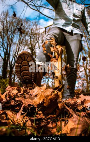 Un homme qui se kicking part dans l'air, ciel bleu, automne Banque D'Images