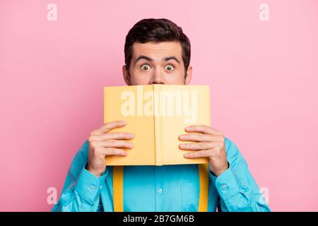 Gros plan portrait de son sympathique gars à bande dessinée effrayée barbu portant une chemise à la menthe tenant à la main se cachant derrière la littérature de lecture de journal Banque D'Images