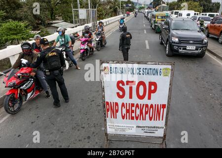 Quezon City. 16 mars 2020. Les policiers de la police nationale philippine (PNP) inspectent les personnes à un point de contrôle à Quezon City, aux Philippines, le 16 mars 2020. Le président philippin Rodrigo Duterte a placé toute l'île principale de Luzon aux Philippines sous la rubrique "renforcement de la quarantaine communautaire" dans une tentative radicale de contenir la propagation de la COVID-19 dans le pays, a déclaré le porte-parole présidentiel Salvador Panelo lundi. Les Philippines ont maintenant 140 cas confirmés de COVID-19, dont 12 décès. Crédit: Rouelle Umali/Xinhua/Alay Live News Banque D'Images