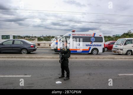 Quezon City. 16 mars 2020. Un policier de la police nationale philippine (PNP) est gardien le long d'une route à un point de contrôle à Quezon City, aux Philippines, le 16 mars 2020. Le président philippin Rodrigo Duterte a placé toute l'île principale de Luzon aux Philippines sous la rubrique "renforcement de la quarantaine communautaire" dans une tentative radicale de contenir la propagation de la COVID-19 dans le pays, a déclaré le porte-parole présidentiel Salvador Panelo lundi. Les Philippines ont maintenant 140 cas confirmés de COVID-19, dont 12 décès. Crédit: Rouelle Umali/Xinhua/Alay Live News Banque D'Images