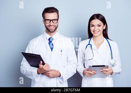 Portrait de deux médecins professionnels qui ont réussi des travailleurs en couches tenant le presse-papiers et la tablette numérique sur fond gris Banque D'Images