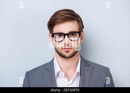 Portrait d'un jeune homme sérieux dans des verres regardant directement dans l'appareil photo avec un regard profond dans des vêtements formels sur fond bleu clair Banque D'Images