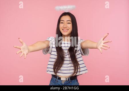 Portrait de charmante fille asiatique angélique avec de longs cheveux brunette et halo sur la tête ouvrant ses mains larges à câlin, accueillant avec le sourire amical, sai Banque D'Images