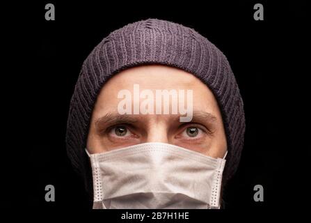 L'homme dans la casquette au masque de protection médicale, anti-infectieux, protection contre le coronavirus. Stare intense à l'appareil photo , gros plan, yeux, ste Banque D'Images