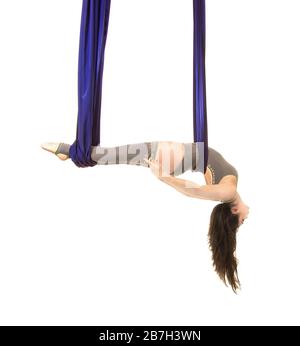 Jeune, souriant acrobat, avec de longs cheveux, dans un costume gris et des leggings faisant des exercices sur la soie bleu aérée . Prise de vue studio sur fond blanc. Banque D'Images