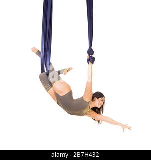 Jeune, souriant acrobat, avec de longs cheveux, dans un costume gris et des leggings faisant des exercices sur la soie bleu aérée . Prise de vue studio sur fond blanc. Banque D'Images