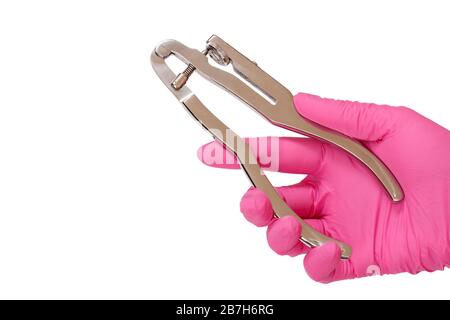 La main du dentiste dans le gant en latex rose avec poinçon dentaire sur fond blanc isilé. Concept d'outils médicaux. Banque D'Images