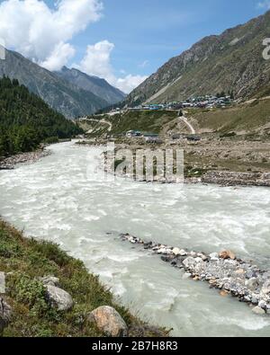 Vue sur la rivière Baspa en direction de l'Himalaya accidenté et du petit village de Chitkul sous le ciel bleu dans l'Himachal Pradeshl, Inde. Banque D'Images