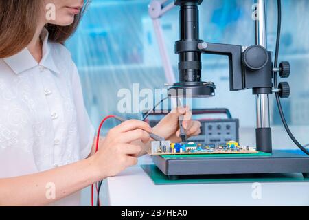 Jeune femme en circuits imprimés inspection concevoir. Laboratoire d'électronique moderne Banque D'Images