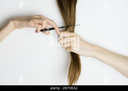 La femme bouleversée coupe ses cheveux longs et droits avec des ciseaux Banque D'Images