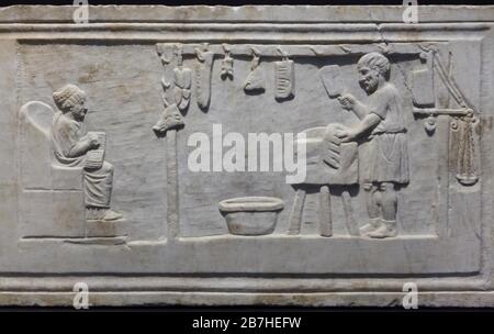 Boucherie représentée dans le tombeau romain relief d'un boucherie de porc daté de 140-150 après J.-C.La boucheuse d'une tunique courte se tient devant un bloc de hachage, hacher des côtes avec un cale à viande.Sa femme est assise en face de lui.Le magasin du boucher avec diverses coupes de porc et des outils de travail est représenté dans le soulagement. Banque D'Images