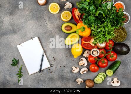 Différents légumes et ingrédients pour cuisiner de délicieux plats. Un livre pour écrire des recettes se trouve sur la table. Espace de copie pour le texte Banque D'Images