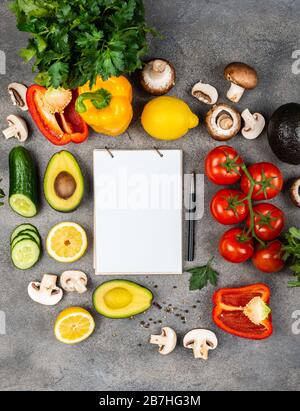 Différents légumes et ingrédients pour cuisiner de délicieux plats. Un livre pour écrire des recettes se trouve sur une table entourée de nourriture. Espace de copie pour le texte Banque D'Images