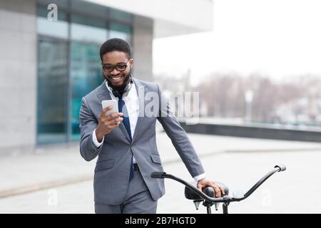 Beau homme d'affaires texting sur téléphone tenant vélo Banque D'Images