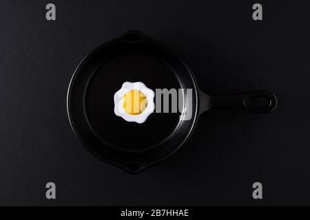 Oeuf frit minimaliste sur poêle à frire en fer et fond noir Banque D'Images