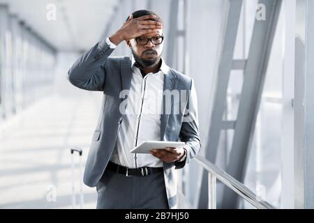 Homme d'affaires africain fatigué touchant tête sentir Bad Walking à l'aéroport Banque D'Images