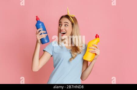 Rire fille choisit une bouteille de fournitures de nettoyage Banque D'Images