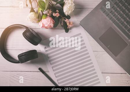 feuille de notes musicales vierge sur la table en bois avec ordinateur portable et casque. vue de dessus Banque D'Images