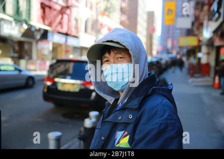 Les gens portent des masques lorsqu'ils marchent le long des rues tranquilles de Chinatown à New York le dimanche 15 mars 2020. Banque D'Images