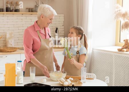 Adorable petite fille aidant sa grand-mère à cuire dans la cuisine, espace vide Banque D'Images