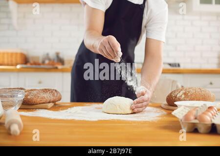 L'homme barbu de Baker fait de la pâte à pain fraîche à une table dans la cuisine de boulangerie. Banque D'Images