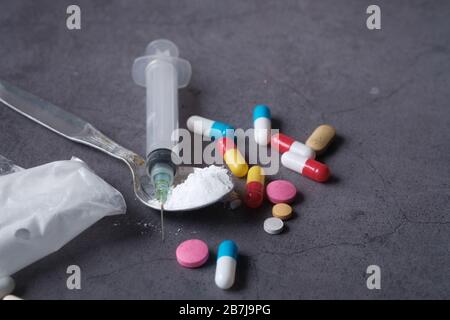 Seringue de drogue avec héroïne cuite sur fond noir. Banque D'Images