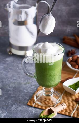 Matcha Latte avec lait d'amande et crème en verre sur fond de pierre grise vertical Banque D'Images
