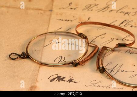 Vintage Pince-nez: gros plan d'un pince-nez vintage couché sur une ancienne feuille manuscrite de papier d'écriture Banque D'Images