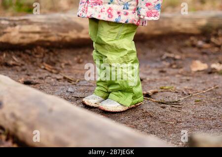 Enfant de 4 ans fille dans des vêtements chauds debout sur le plancher forestier entre quelques troncs d'arbres au début du printemps en mars n Allemagne Banque D'Images