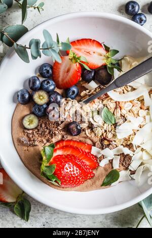 Le petit déjeuner est magnifique avec de la granola, des baies et de la noix de coco dans un bol blanc. Banque D'Images