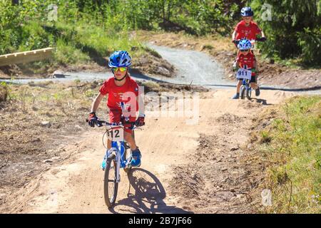 Des enfants qui font du vélo sur une piste de pompe par une journée ensoleillée. Banque D'Images